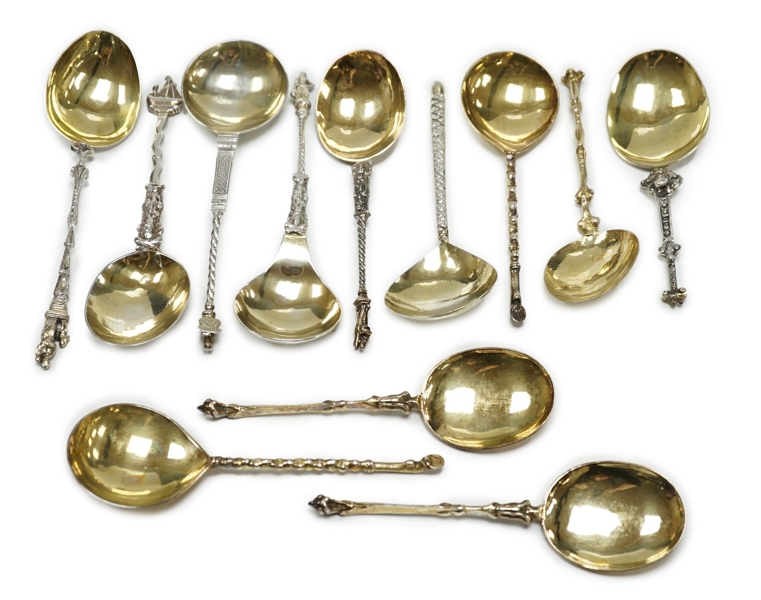 Twelve assorted 19th century and later Scandinavian or Dutch? gilt or parcel gilt white metal spoons, with differing stems including apostle, largest 18.8cm, 19.3oz.